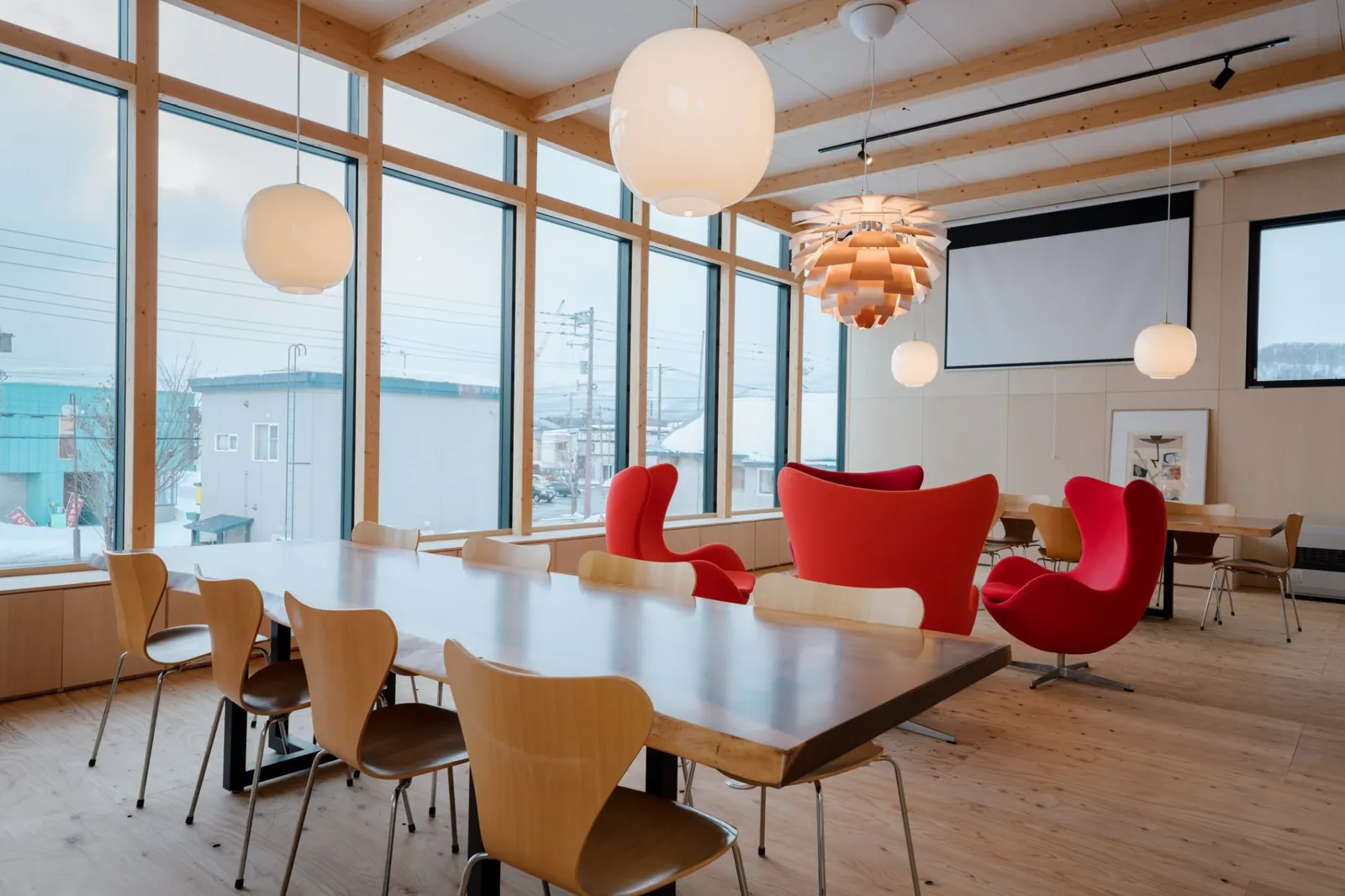 Dining space with red egg chairs and tall windows, AK Housing, Niseko