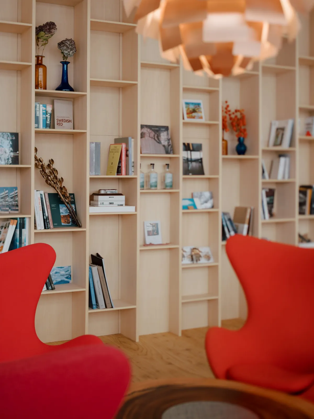Library wall with red lounge chairs, AK Housing, Niseko