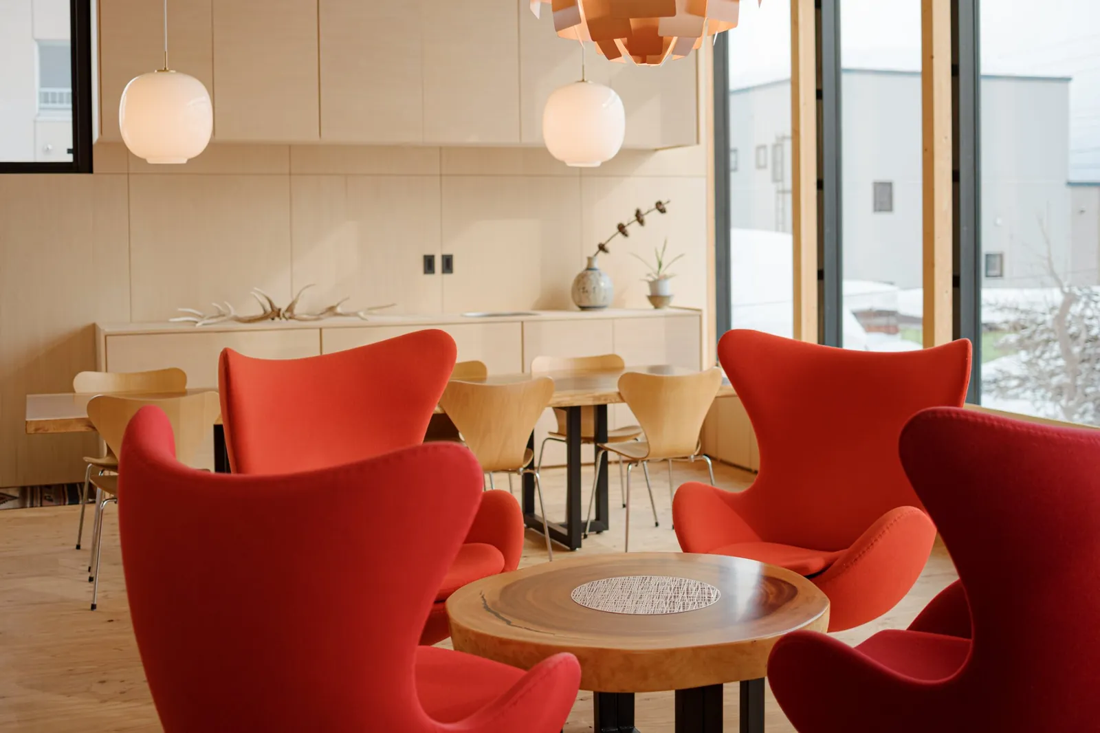 Lounge with red chairs and winter light, AK Housing, Niseko