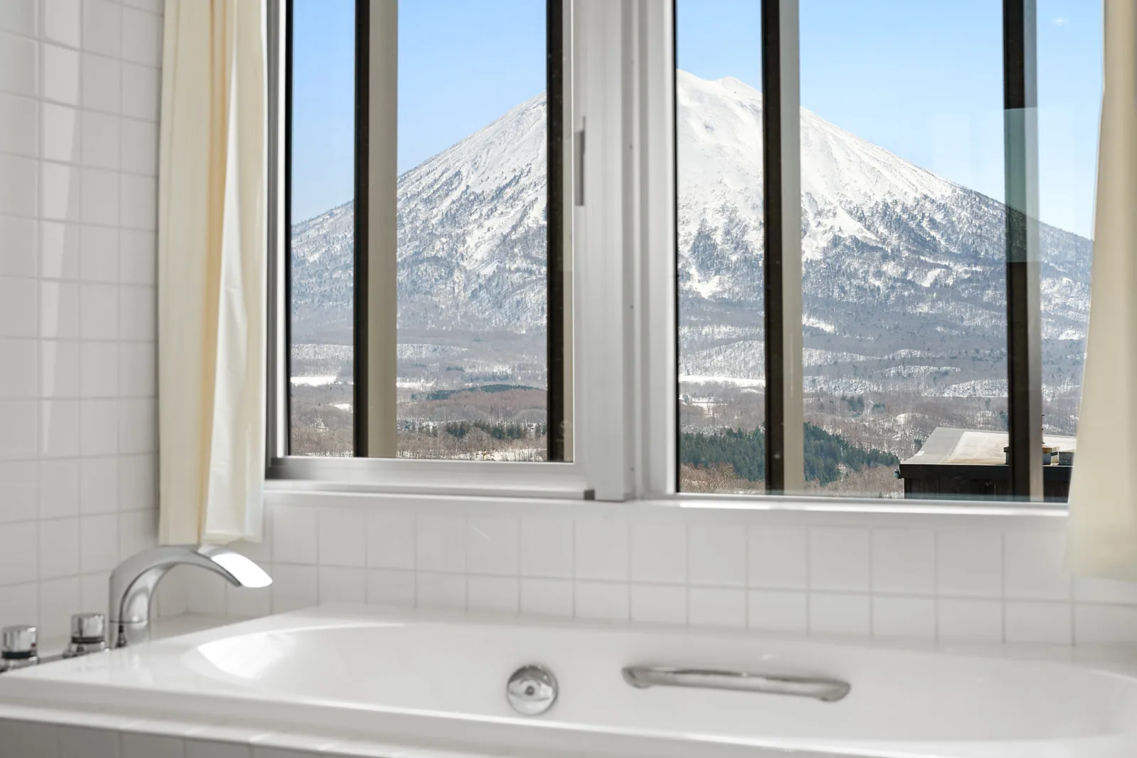 Bathtub below a window framing Mount Yotei at Alpen Ridge Hotel Niseko