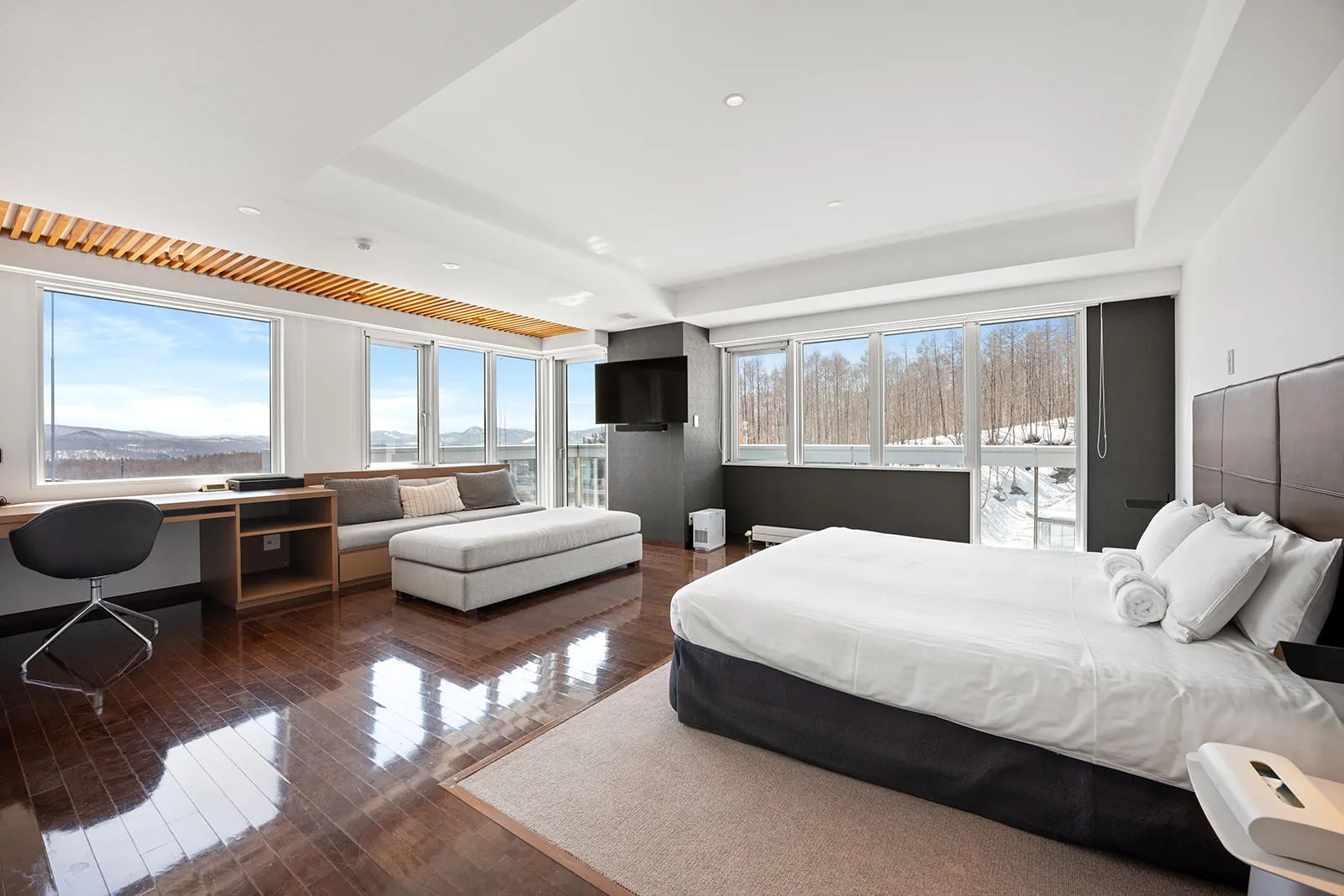 Bedroom with desk, daybed and corner windows at Alpen Ridge Hotel Niseko
