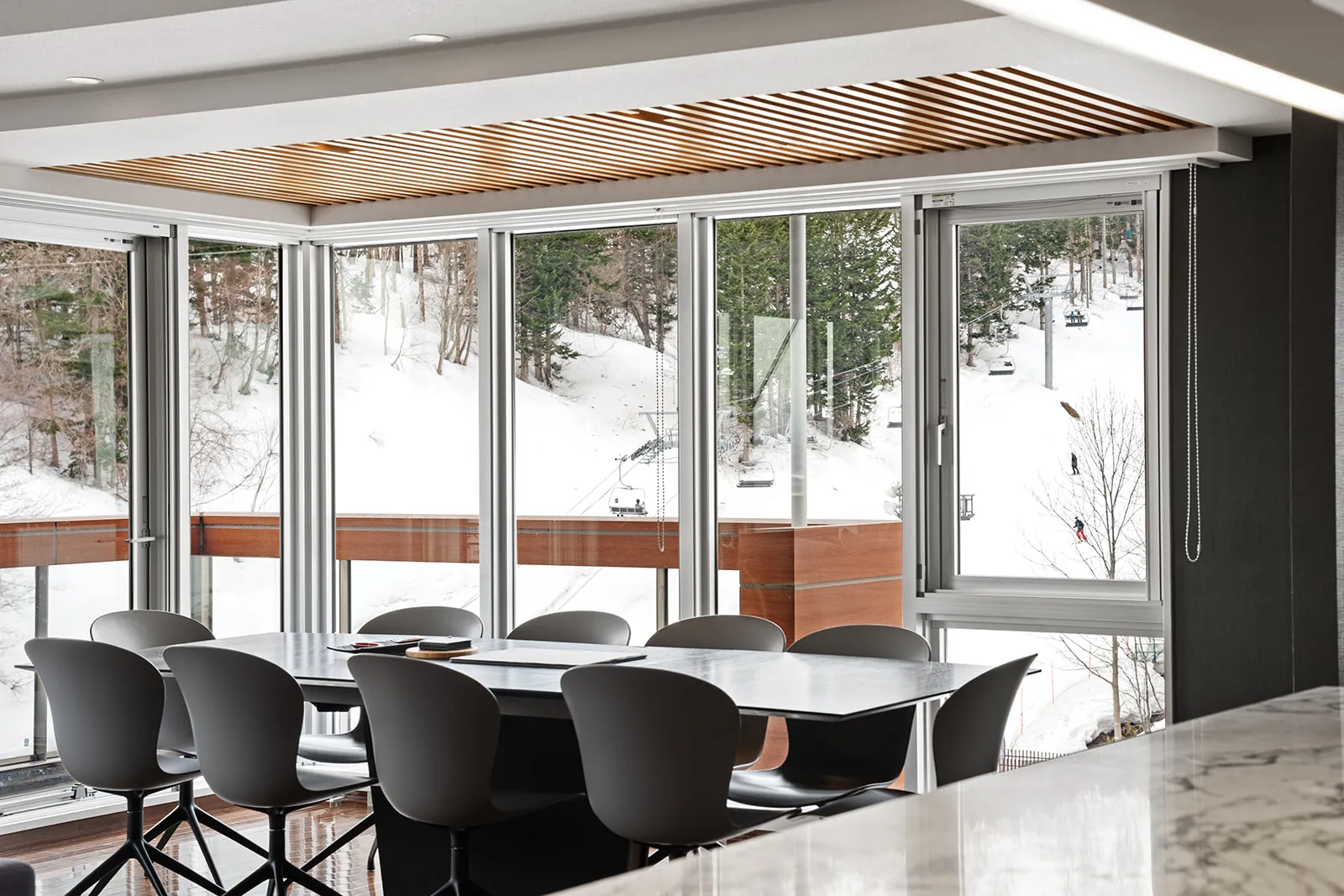 Dining table beside full height windows looking onto the ski slope at Alpen Ridge Hotel Niseko