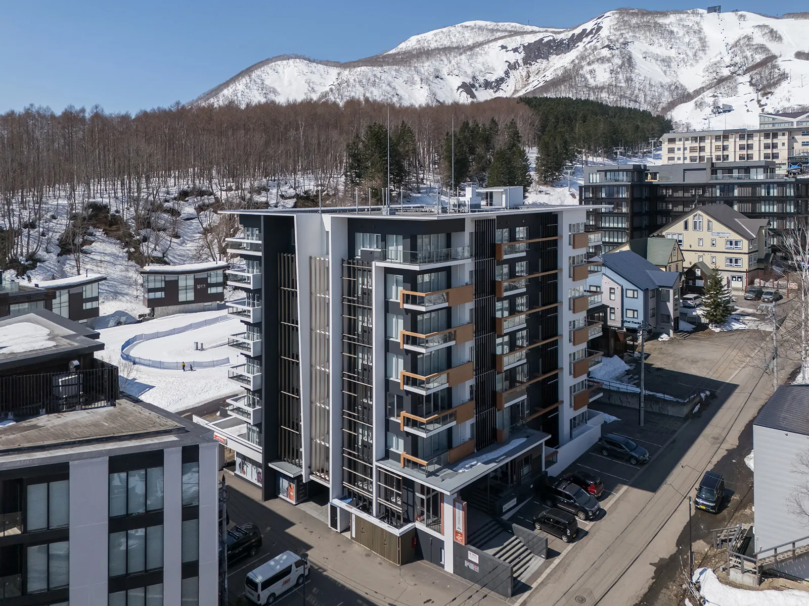Drone view of Alpen Ridge Hotel Niseko in Hirafu village with the ski slopes of Mount Niseko Annupuri behind