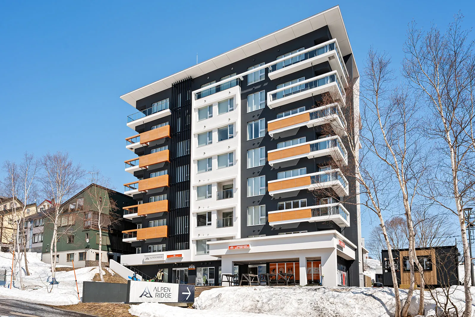 Alpen Ridge Hotel Niseko facade and entrance sign in Hirafu, with birch trees and a clear winter sky