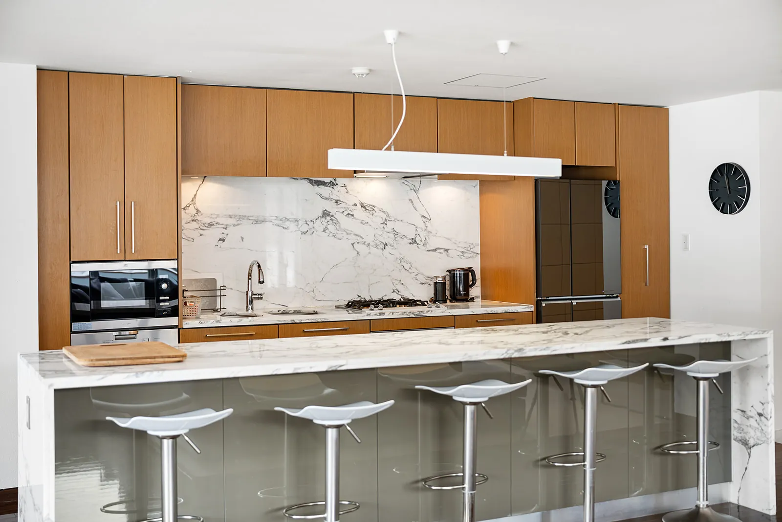 Marble kitchen island with bar stools and timber cabinetry at Alpen Ridge Hotel Niseko