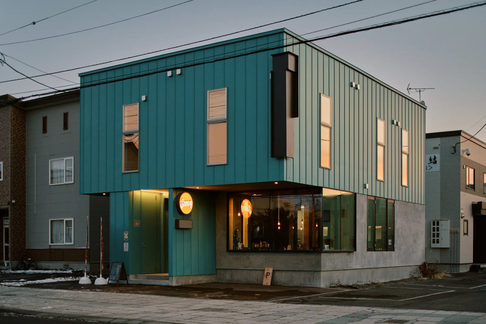 Snowy Cafe Niseko teal building lit at dusk
